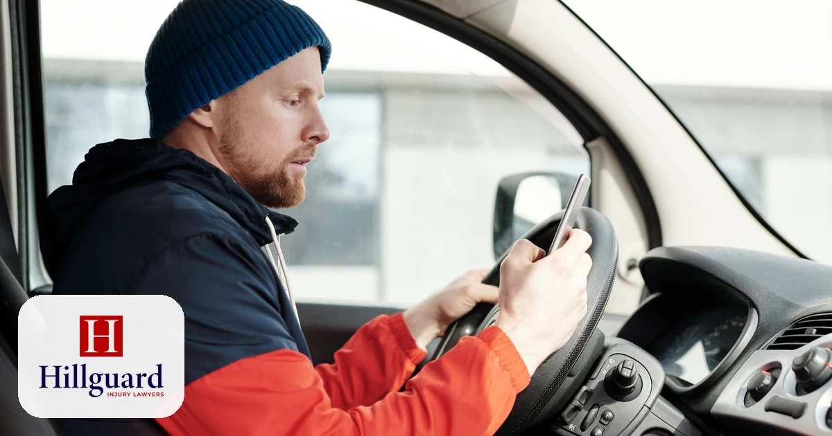 Distracted driver looking at a phone and texting behind the wheel instead of watching the road