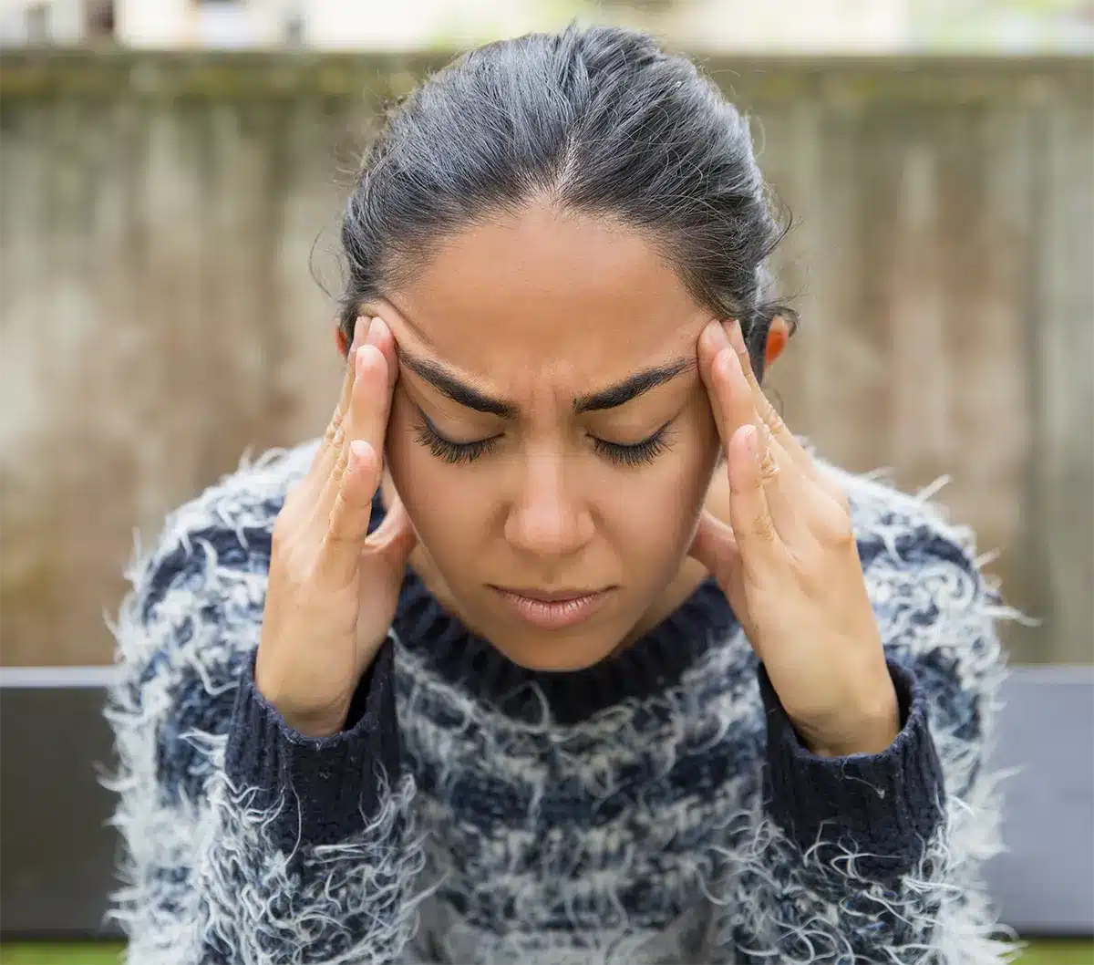 tired pretty young woman touching temples outdoors img